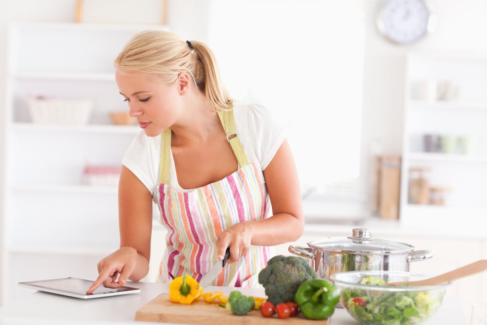 Blonde woman using a tablet computer to cook in her kitchen