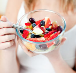 Close-up of a woman eating a fruit salad at home