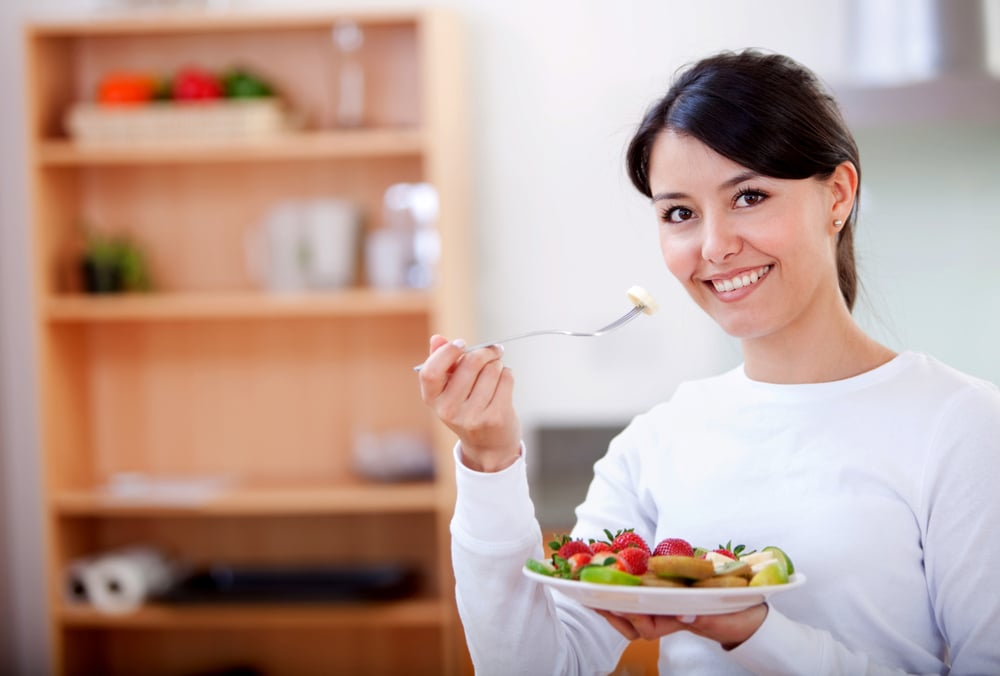Healthy eating woman with fruit salad smiling